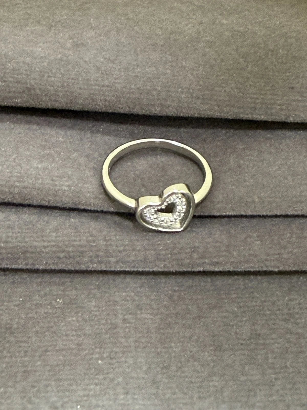 Silver ring with a heart-shaped design on a gray surface