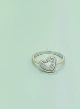 Heart-shaped silver ring with small diamonds on a light green background