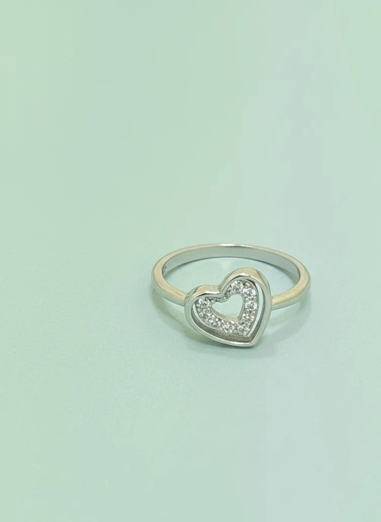 Heart-shaped silver ring with small diamonds on a light green background