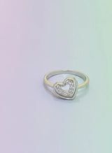 Heart-shaped ring with embedded stones on a gradient background