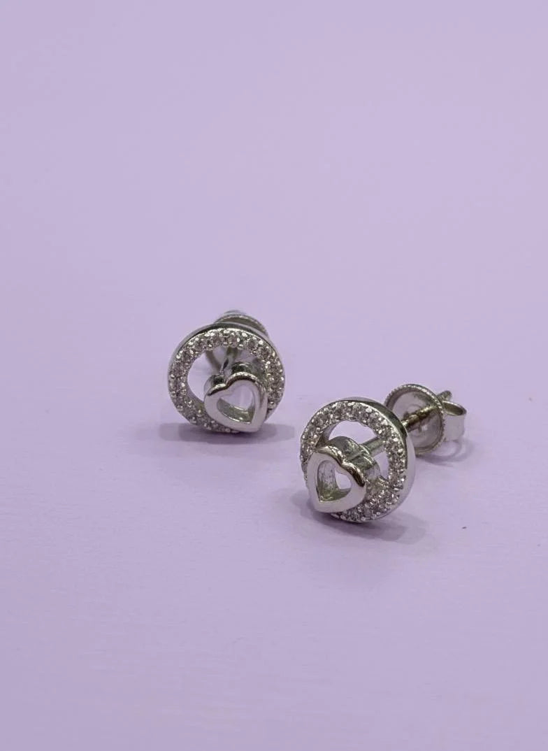 Pair of silver earrings with heart design on a light purple background