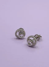 Pair of silver earrings with heart design on a light purple background