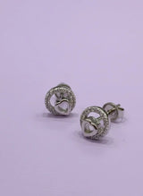 Pair of silver earrings with heart design on a light purple background