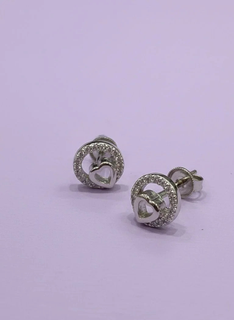 Pair of silver earrings with heart design on a light purple background