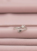 Silver hug ring on pink fabric background