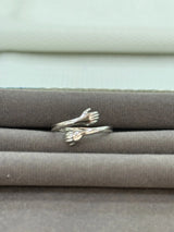 Silver ring with hug design on a textured surface