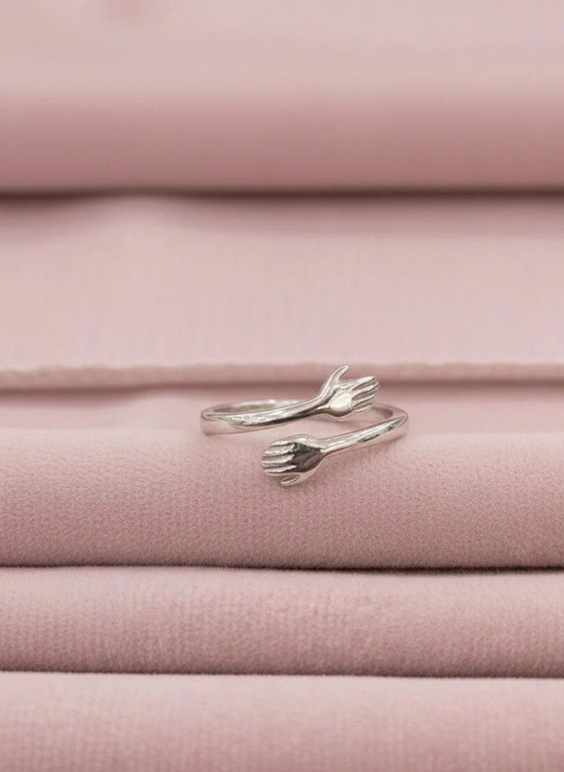 Silver hug ring on pink fabric background