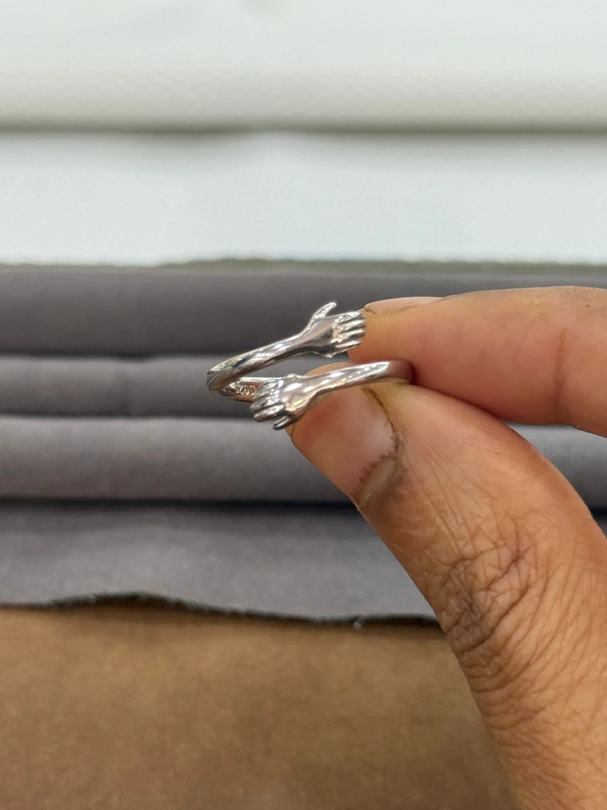 Silver ring being held on a finger with a neutral background