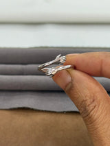 Silver ring being held on a finger with a neutral background