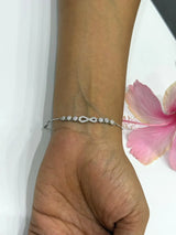 Silver bracelet on a wrist with a pink flower in the background