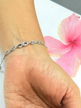 Silver bracelet on a wrist with a pink flower in the background