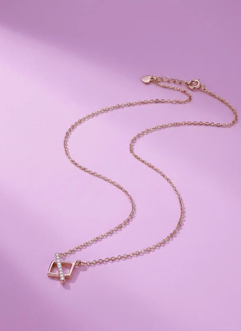 Rose gold necklace with a geometric pendant on a pink background