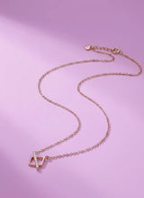 Rose gold necklace with a geometric pendant on a pink background