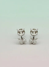 Pair of silver earrings with leaf design on a light gray background