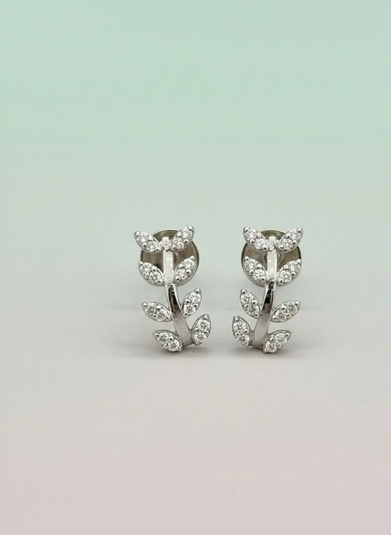 Pair of silver earrings with leaf design on a light gray background