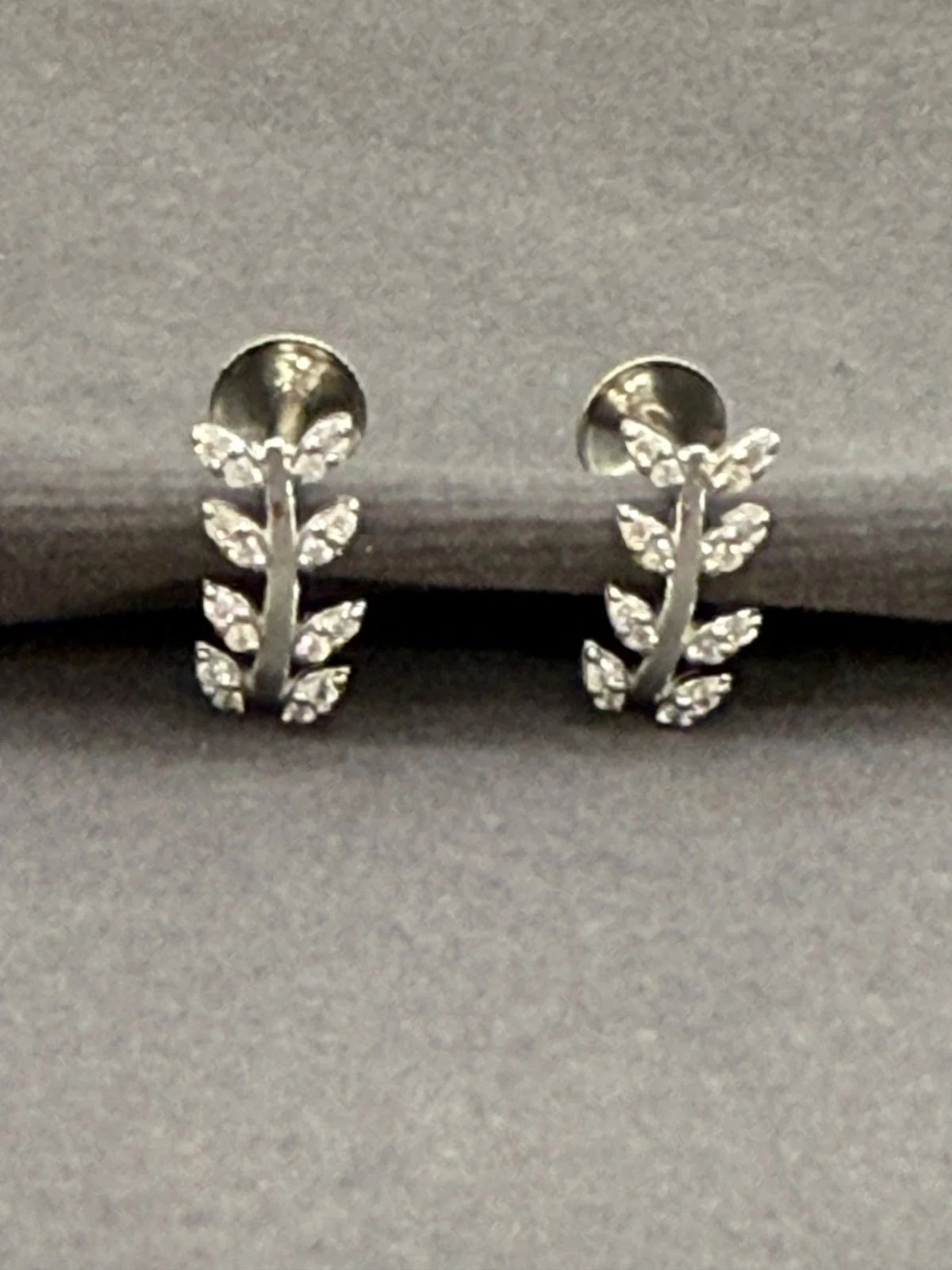 Silver leaf-shaped earrings on a gray background