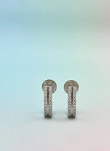 Pair of silver earrings with small stones on a gradient background