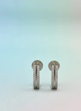 Pair of silver earrings with small stones on a gradient background