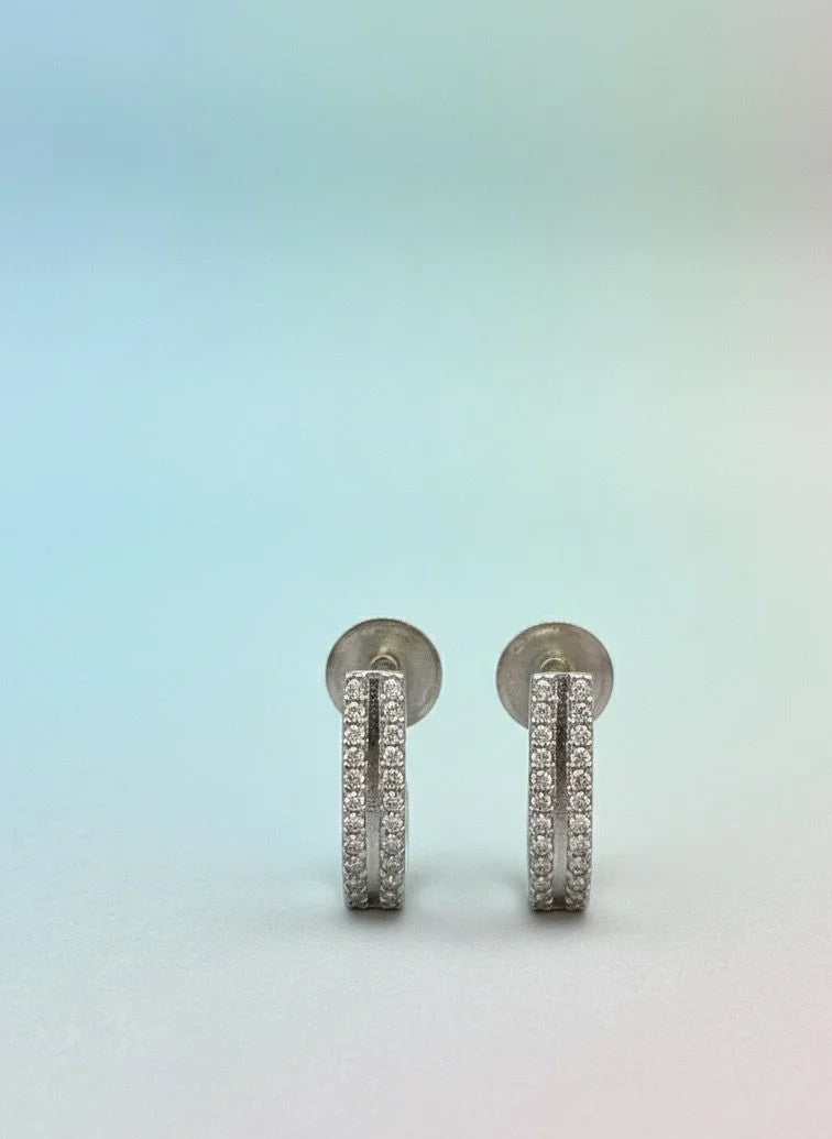 Pair of silver earrings with small stones on a gradient background