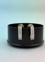 Pair of silver hoop earrings on a black stand with a gradient background