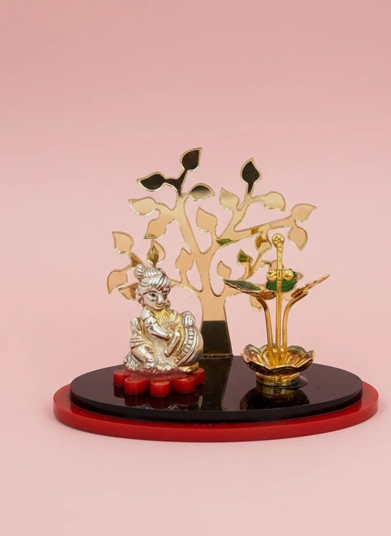 Decorative item with a figure, tree, and red base on a pink background