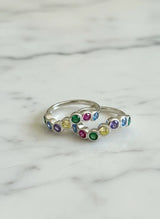 Silver toe ring with colorful gemstones on a marble background