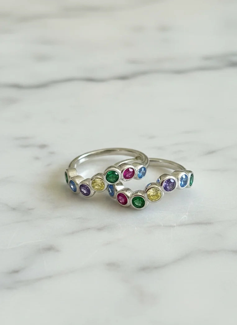 Silver toe ring with colorful gemstones on a marble background