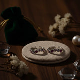 Two toe rings with gemstones on a textured surface with decorative elements.