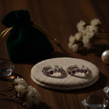 Two silver toe rings with gemstones on a textured surface with decorative elements.