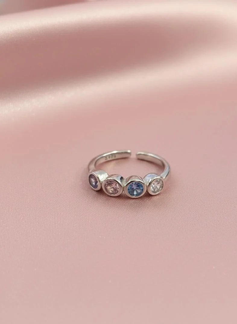 Silver toe ring with embedded stones on a pink fabric background