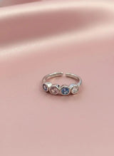 Silver toe ring with embedded stones on a pink fabric background