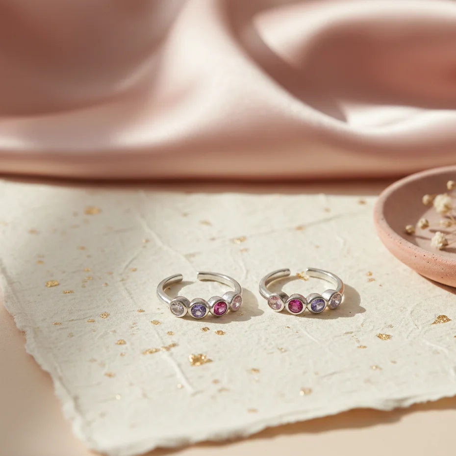 Silver toe rings with colorful stones on a light surface
