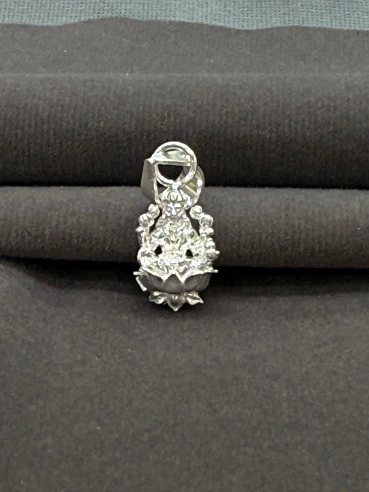 Silver pendant on a gray fabric background