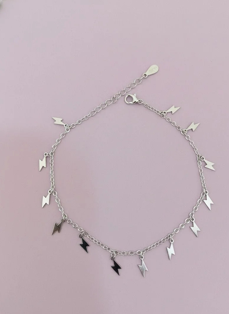 Silver Bracelet with lightning hangings on a light pink background