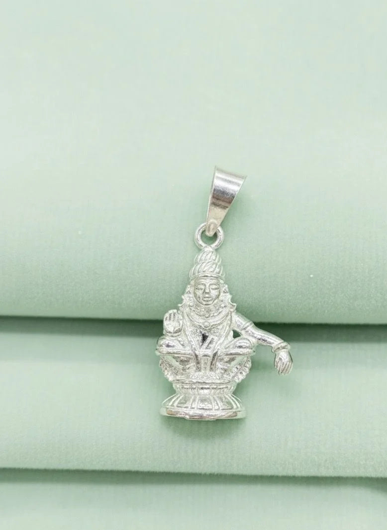 Silver pendant of a deity on a light green fabric background