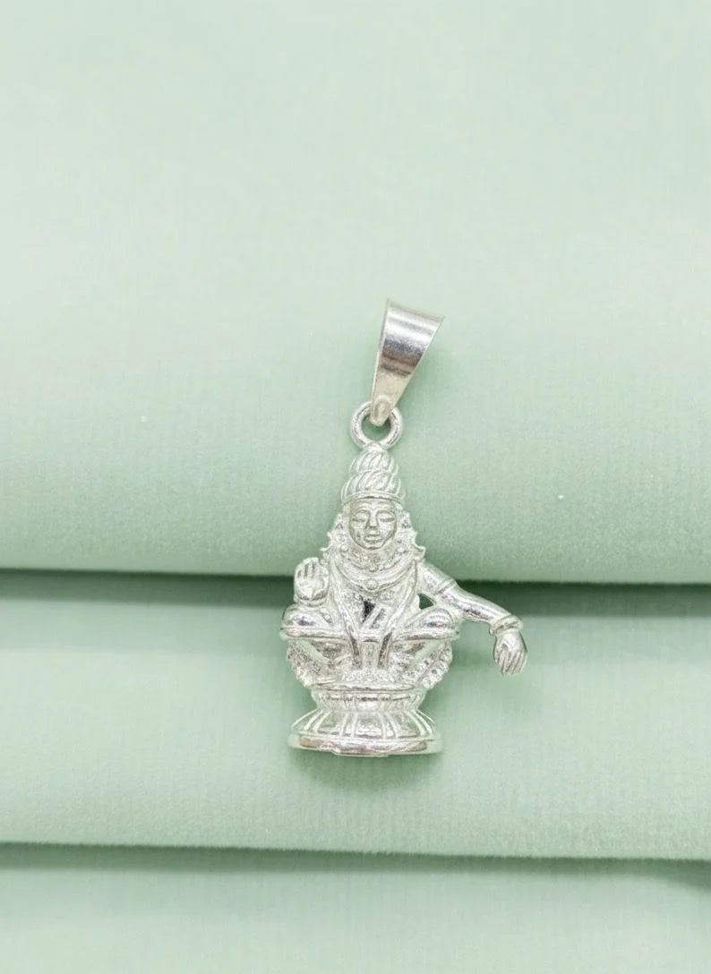 Silver pendant of a deity on a light green fabric background