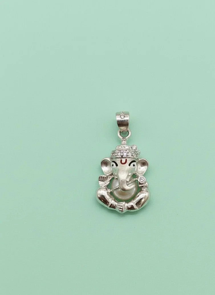 Silver pendant with a deity head design on a light green background