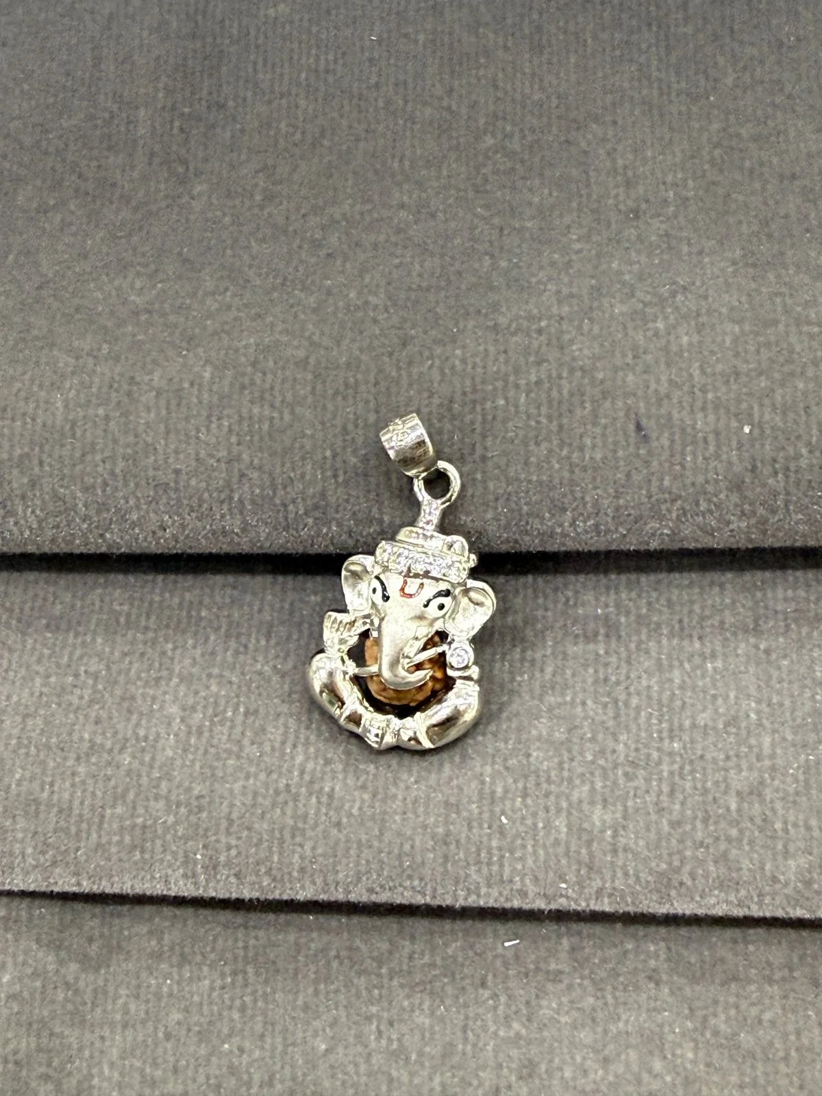 Silver pendant with a face design on a gray surface