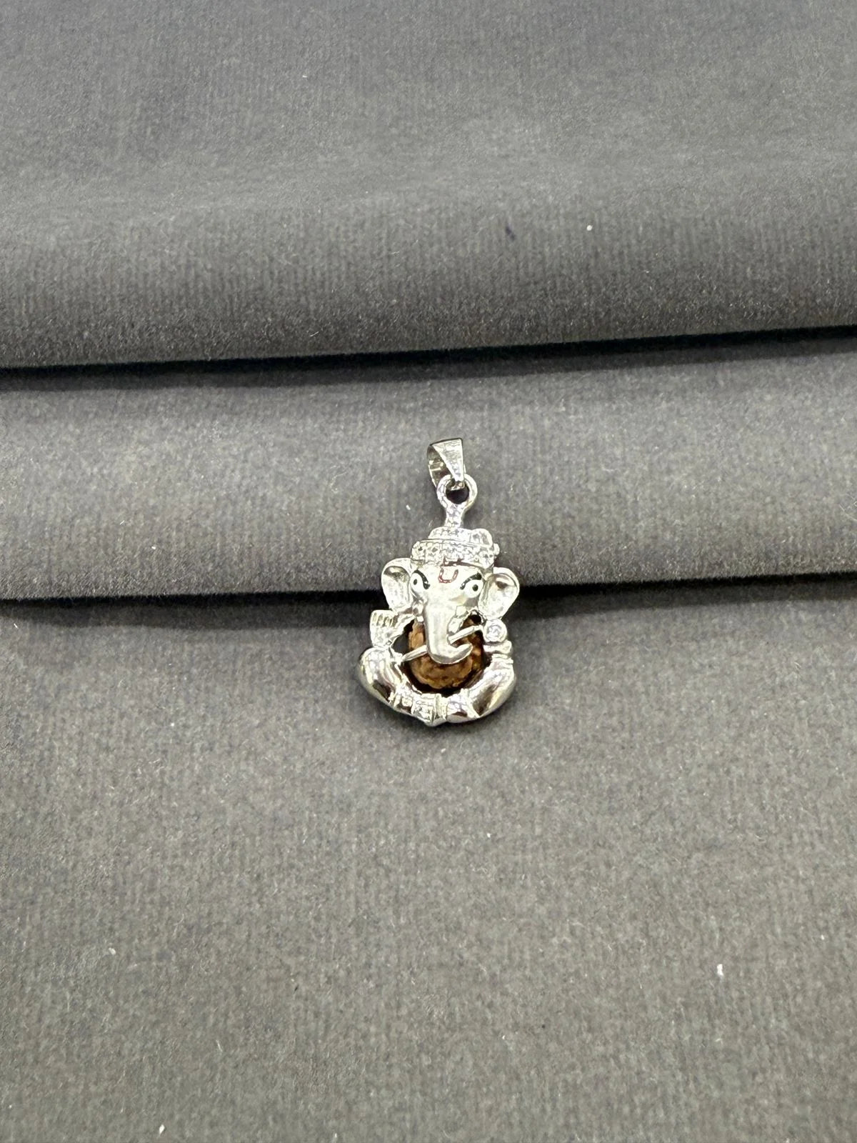 Silver pendant with a face design on a gray fabric background