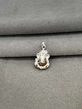 Silver pendant with a face design on a gray fabric background