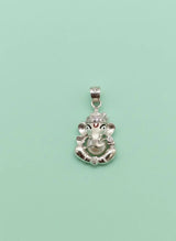 Silver pendant with a deity head design on a light green background