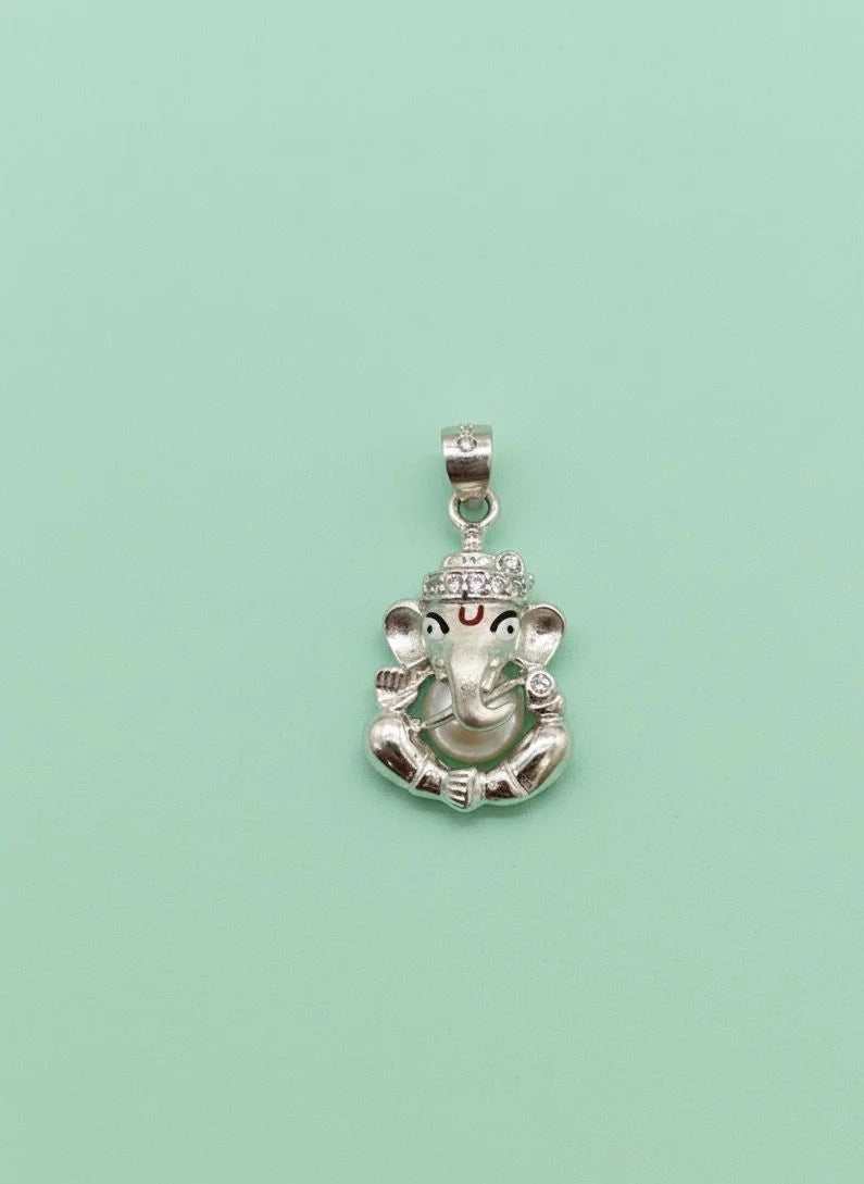 Silver pendant with a deity head design on a light green background
