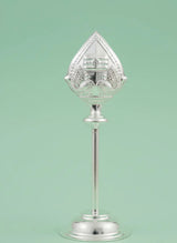 Decorative silver object with a clear glass top on a light green background