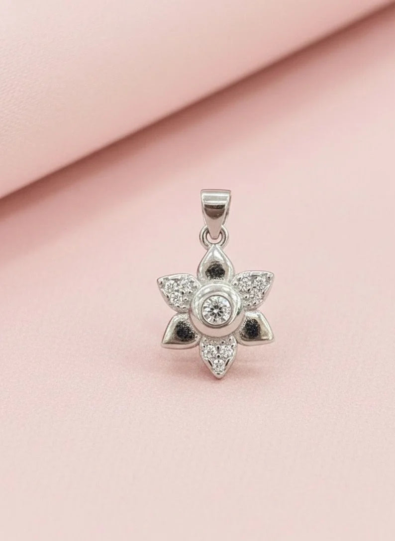 Silver star-shaped pendant with clear stones on a pink fabric background