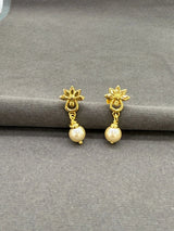 Gold earrings with pearl drops on a gray surface