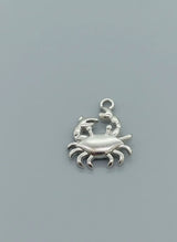 Silver crab charm on a gray background