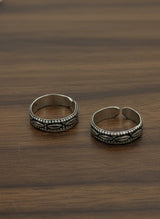 Two silver toe rings on a wooden surface