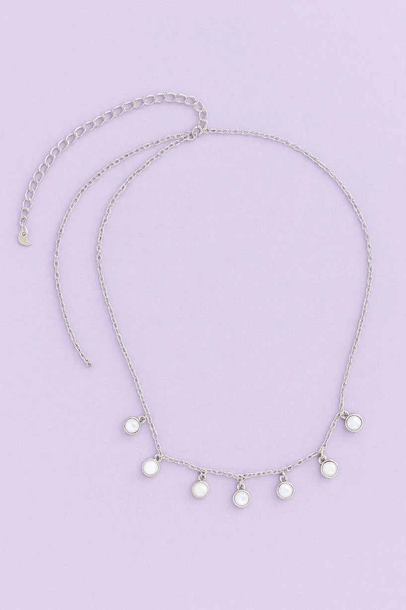 Silver necklace with small round pendants on a light purple background