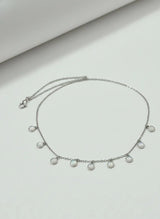 Silver necklace with pearl-like beads on a light gray background