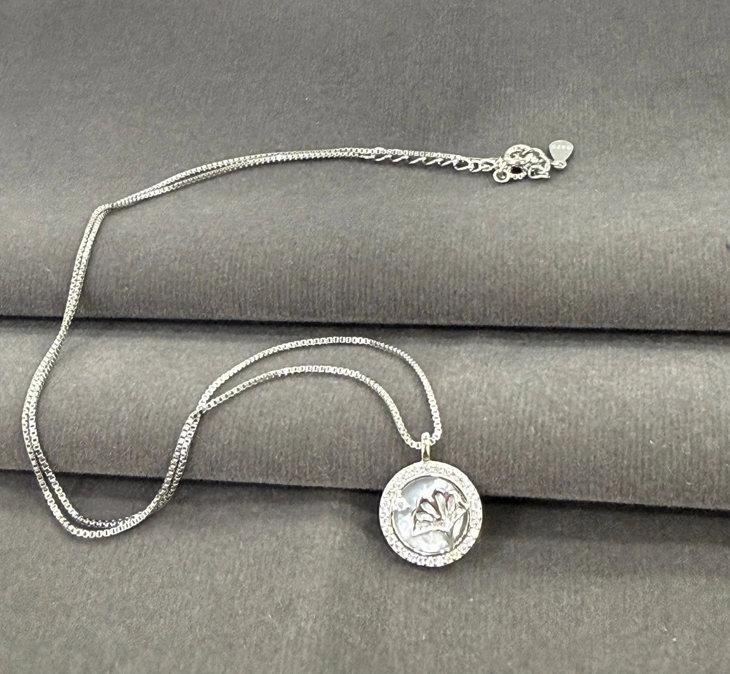 Silver necklace with a pendant on a gray surface